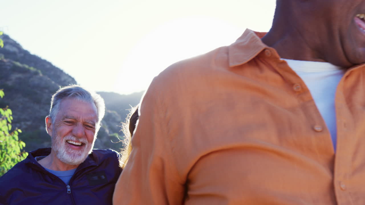 Group Of Smiling Senior Friends Walking In Countryside Together Against Flaring Sun