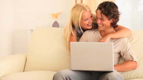 pareja feliz en un sofá con una computadora portátil