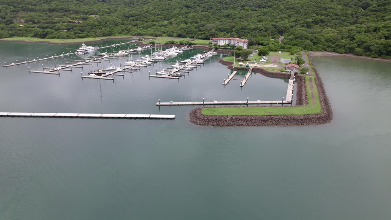 숲, 나카스콜로 해변, 파파가요 반도, 코스타리카로 덮인 언덕 해안 근처의 부두에 주차된 보트에서 공중 팬 오른쪽으로 낮추기