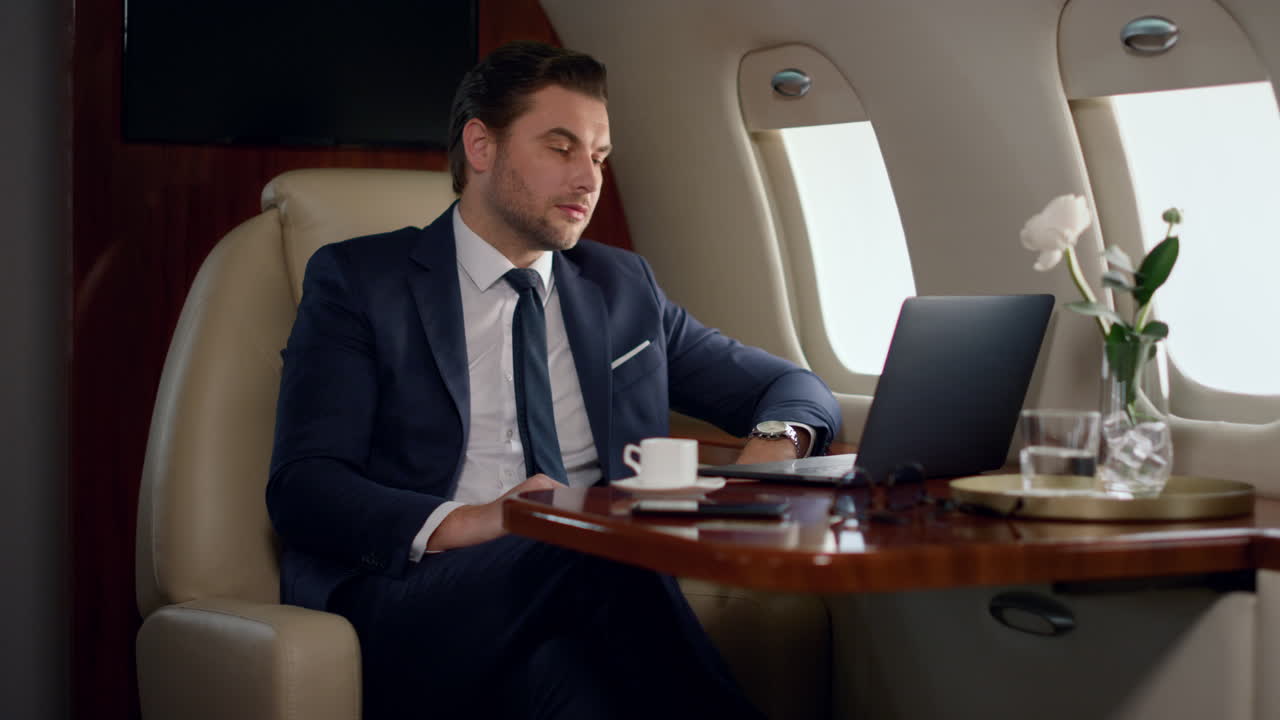 Serio uomo d'affari in videochiamata con il partner su un jet privato. CEO concentrato che parla online.