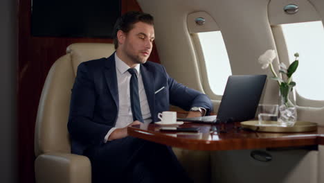 serious businessman videocalling partner in private jet. focused ceo talk online