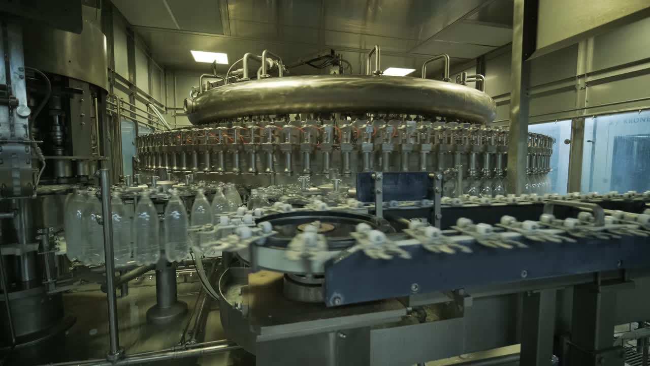 Automatic filling machine pours water into plastic PET bottles at modern beverage plant