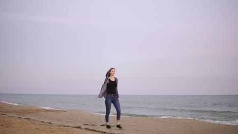 Attractive-young-woman-with-long-hair-holding-colorful-kite-flying-in-the-sky-and-walking-on-the-beach-in-the-evening-during