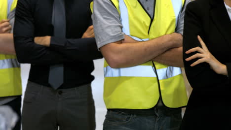 mid section of coworkers standing with arms crossed