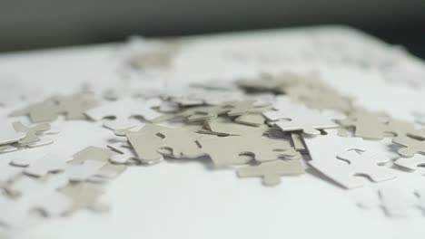 white and gray puzzle pieces laying randomly on a white surface with a dark background