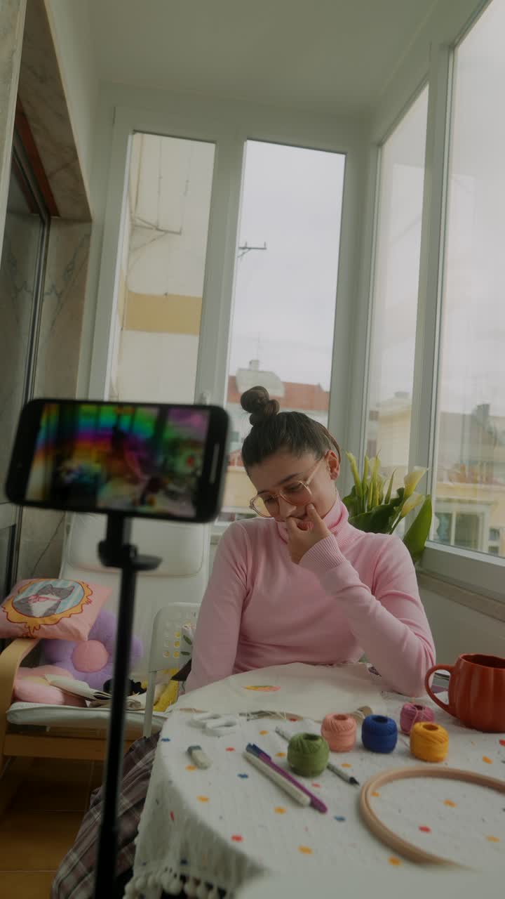 Giovane donna che realizza un vlog su ricamo e artigianato a casa