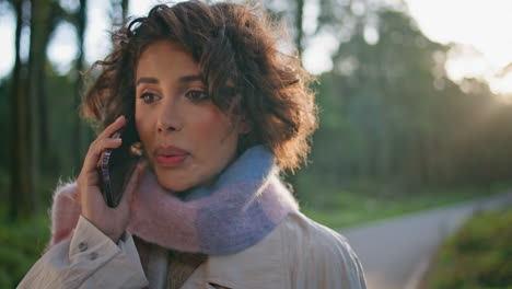 worried lady calling cell phone on nature closeup. woman talking cellphone