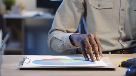 close up view of office worker speaking on the phone and flipping pages of documents with charts and graphics