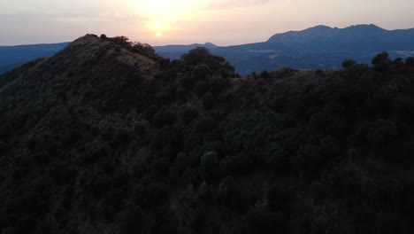 A-drone-rises-over-a-mountain-ridge,-Pico-De-Los-Reales-in-Estepona,-Spain