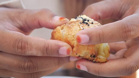 person holding a bite-sized cheese pastry