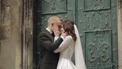 novia y novio besándose frente a las puertas de la iglesia