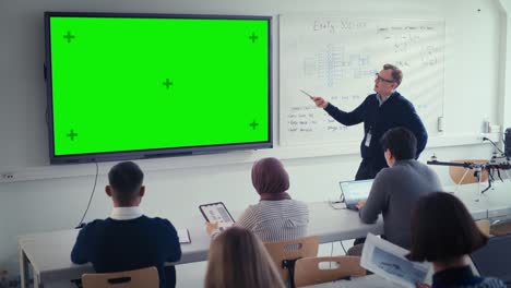 el maestro masculino utiliza una maqueta verde horizontal, una pantalla verde, una pizarra digital interactiva para explicar la lección a un grupo diverso de estudiantes. concepto de ciencia y educación