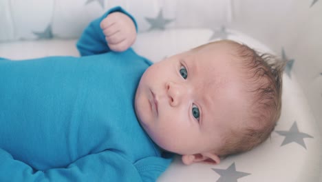 funny little child in blue clothes rests in modern cocoon