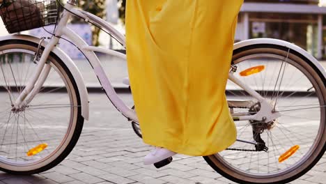 Close-Up-view-of-a-white-city-bicycle-wheels-spinning.-citibike-with-a-bell,-basket-and-flowers.-Unrecognizable-woman-riding-a