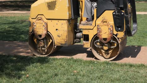 trabajador de la construcción usando un compactor de rodillos para pavimentar una carretera