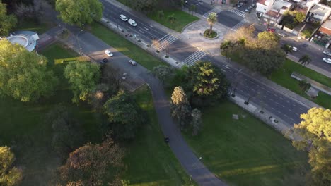 Luftaufnahme-Eines-Autos,-Das-Während-Des-Sonnenuntergangs-Auf-Dem-Pfad-Des-Sarmiento-Parks-In-Buenos-Aires-Fährt---Kamerafahrt---Schöne-Bunte-Baumkronen-Während-Des-Herbsttages