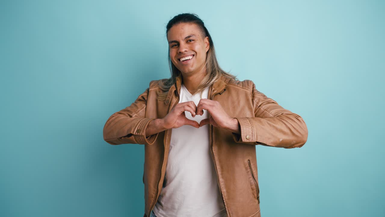 Giovane uomo che manda un bacio e forma un cuore con le mani