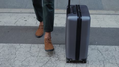 man walking with suitcase across crosswalk