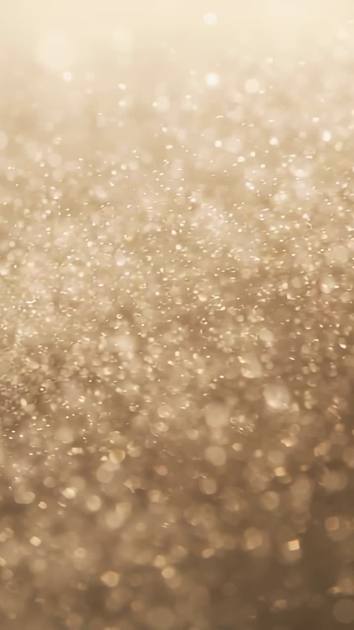 Video verticale: luce pulsante che anima glitter dorati con messa a fuoco variabile, scintillanti con effetto bokeh in studio.