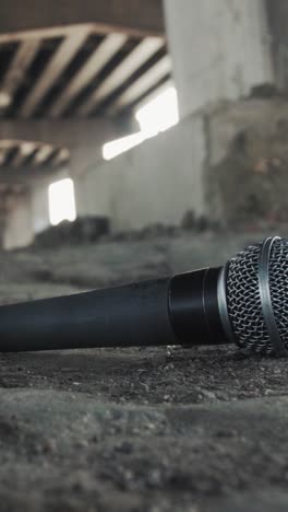 smooth pan reveals dusty handheld mic and loose cable on gritty ground beneath a concrete highway overpass