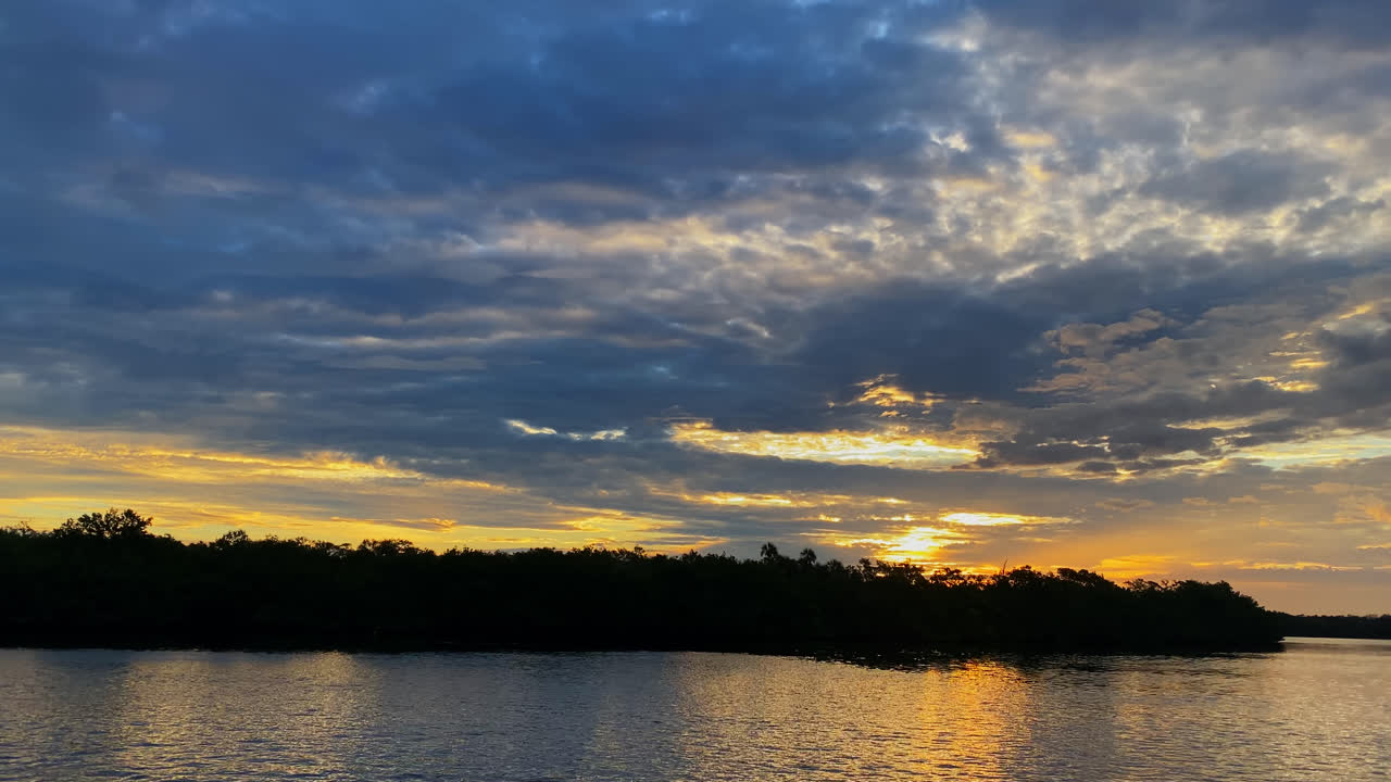 toma cinematográfica de un hermoso cielo de amanecer sobre el océano y el bosque de manglares en la bahía de cucarachas recortada en el fondo