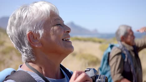 Happy-senior-biracial-couple-in-mountains-taking-photos-on-sunny-day,-in-slow-motion