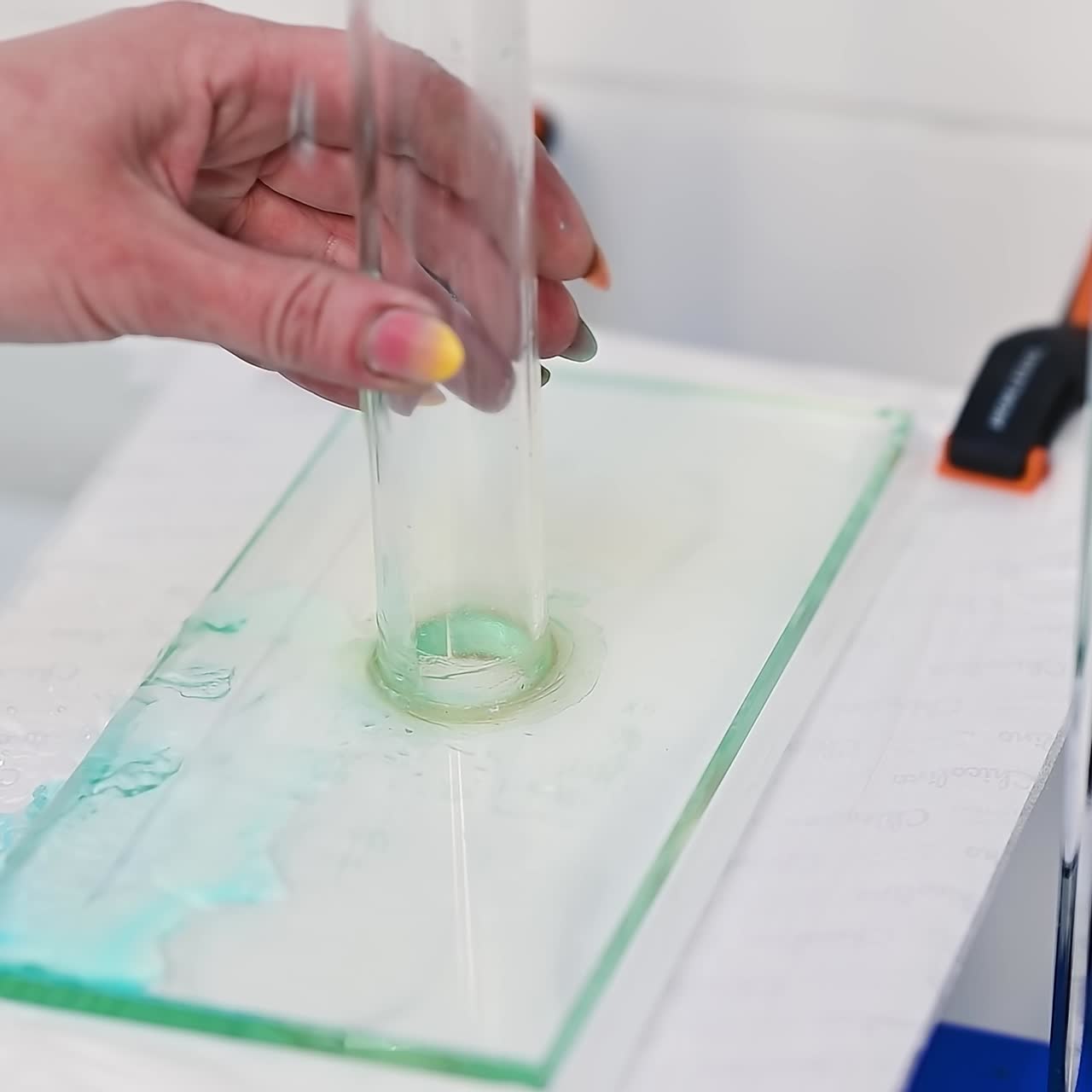 Water is poured by the glass tube onto the diaper material. The hand of the researcher corrects the position of the glass tube. Examination of fabrics for diapers and their absorption ability