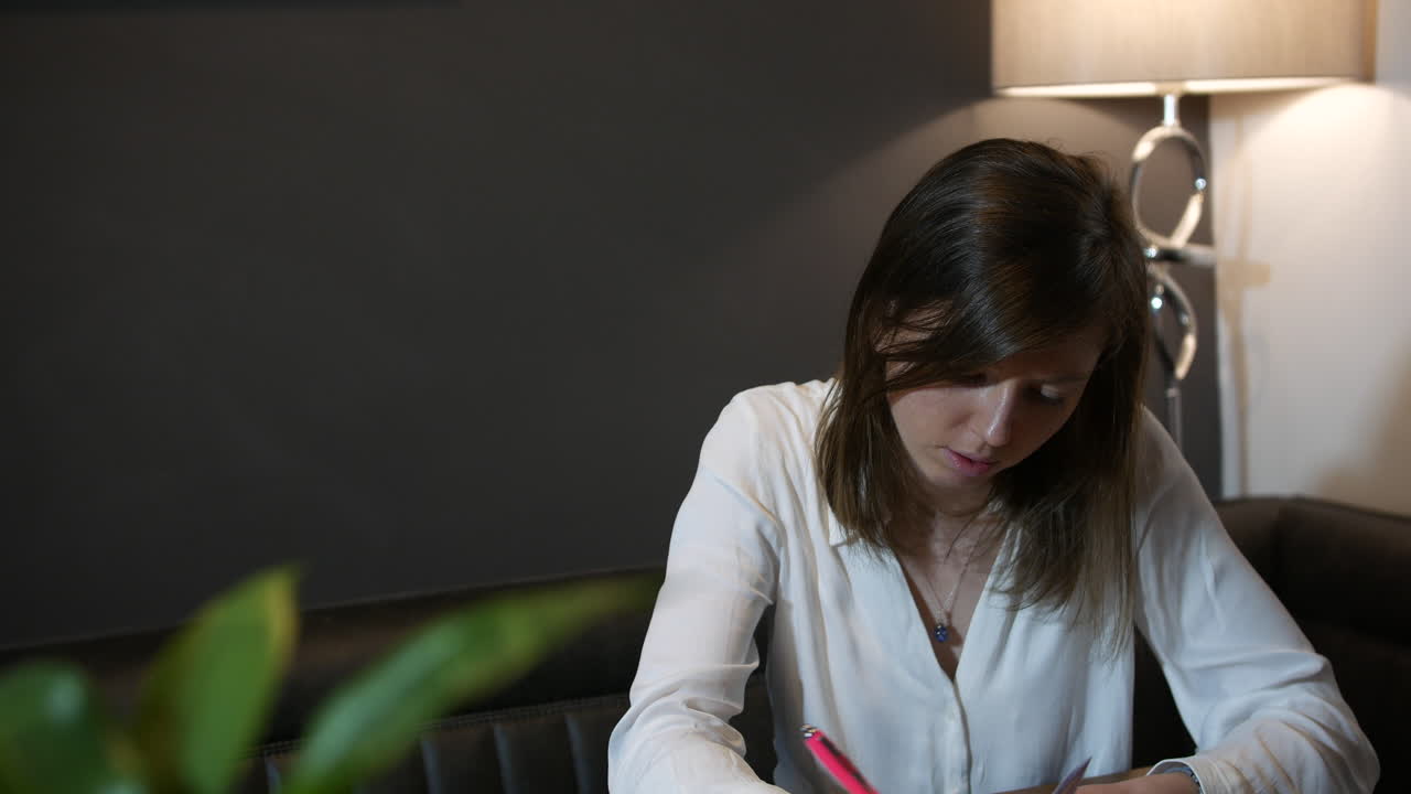 집에서 서류 작업을 하는 젊은 전문가는 바게 보이고 스트레스를 받으며 글을 쓰고 메모를 합니다.