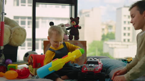 niños alegres jugando en casa. hermanos felices sentados en el suelo entre juguetes.