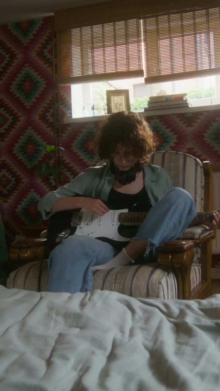 Ragazza adolescente che suona la chitarra in una camera da letto accogliente