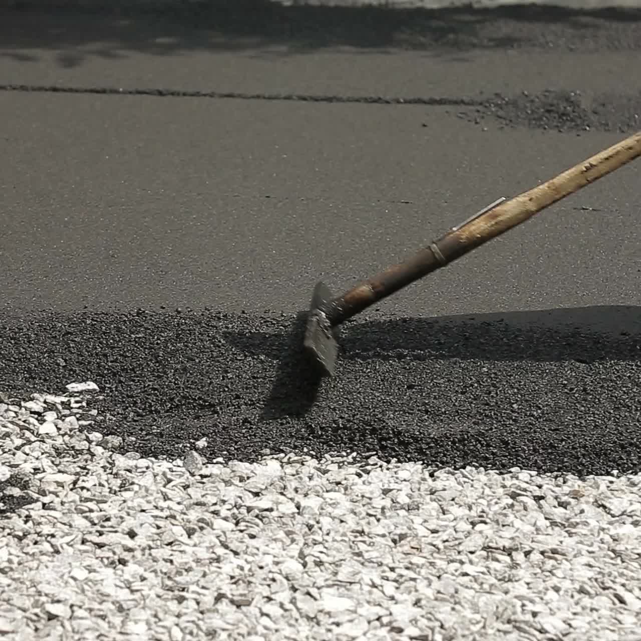 Worker Leveling Fresh Asphalt