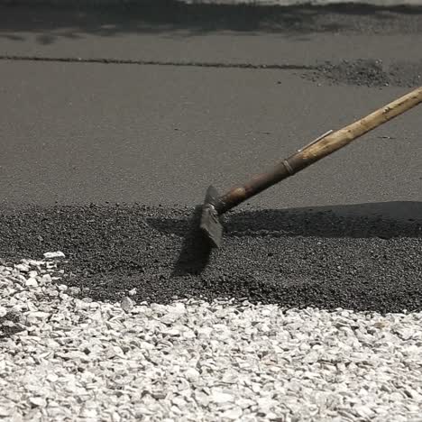 worker leveling fresh asphalt
