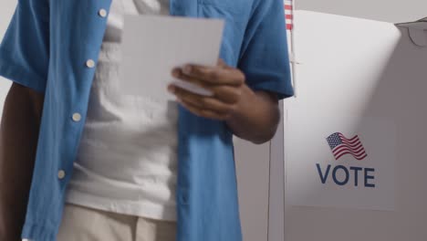 close up of man next to booth with ballot paper in american election deciding how to cast his vote 1