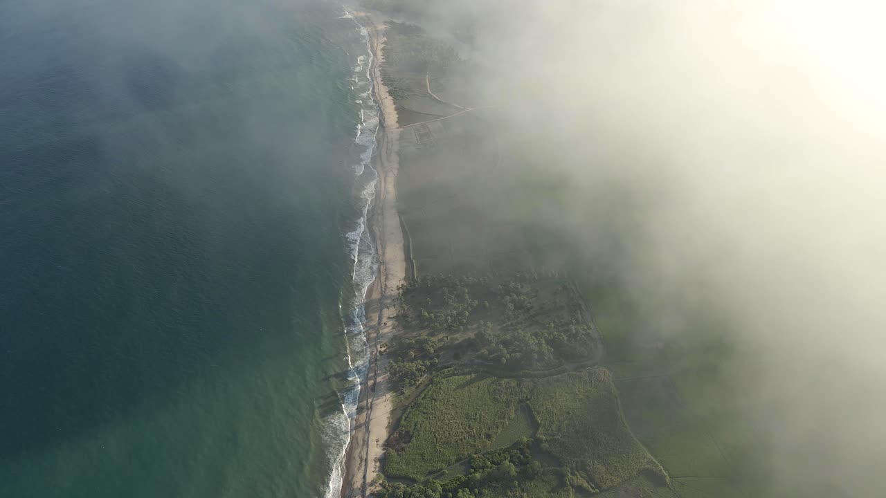 красивая кинематографическая съемка с беспилотного летательного аппарата тропического берега, проступающего сквозь облака