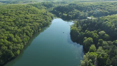 Aerial-over-mountain-lake-later-in-the-day-near-a-campground-with-smoke-coming-from-the-trees-indicating-people-camping-and-grilling-food