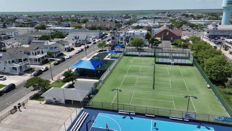 coastal american town with mix of traditional and modern homes. visible sports complex with tennis and basketball courts surrounded by beach-style suburban architecture.summer day in new jersey.aerial
