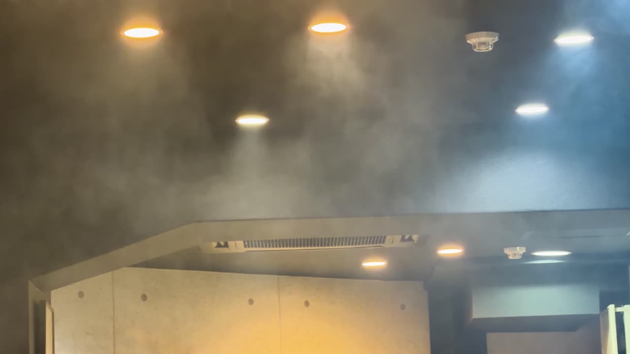 Dichter weißer Rauch und Dampf steigen zu beleuchteten Deckenlüftungen in einem dunklen japanischen Restaurant auf.
