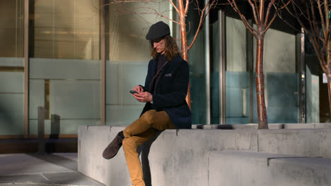 Vista-Lateral-De-Un-Joven-Caucásico-Usando-Un-Teléfono-Móvil-En-La-Ciudad-4k