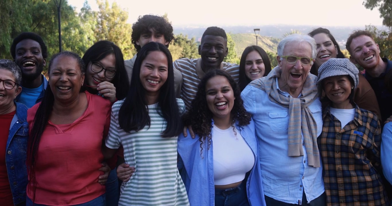 Gruppo multigenerazionale e diversificato felice che sorride alla macchina fotografica all'aperto