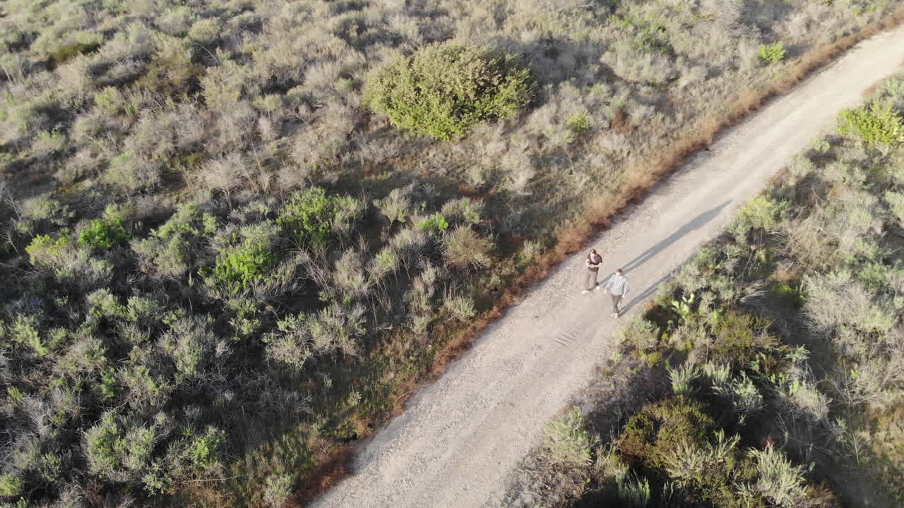 4K Rotating aerial drone shot of two friends hiking in the mountains together.