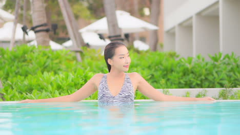 beautiful young asian woman relax and smile in swimming pool of resort for holiday