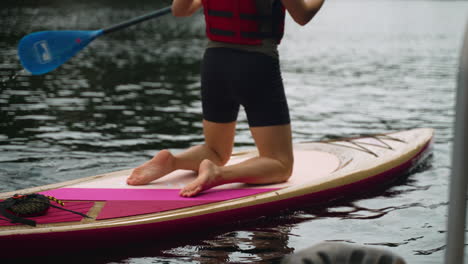 las rodillas de una mujer mientras comienza a remar en una tabla de remo