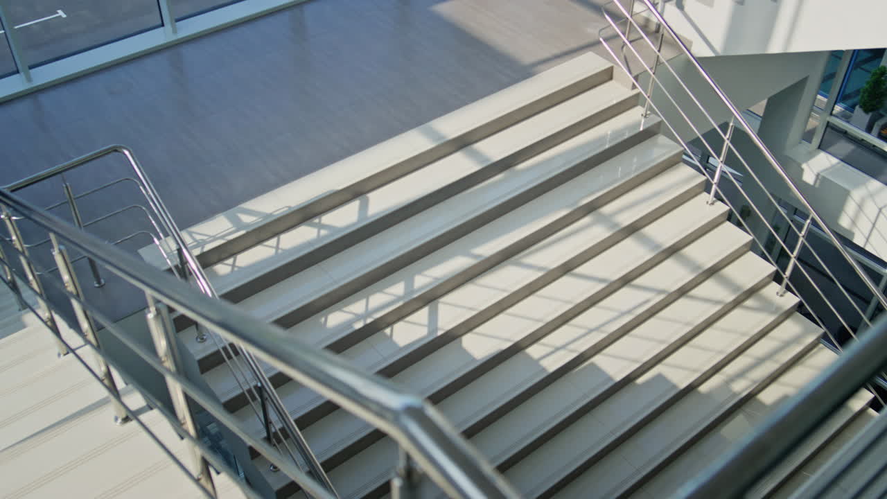 Corporate leader talking mobile phone walking down staircase modern building