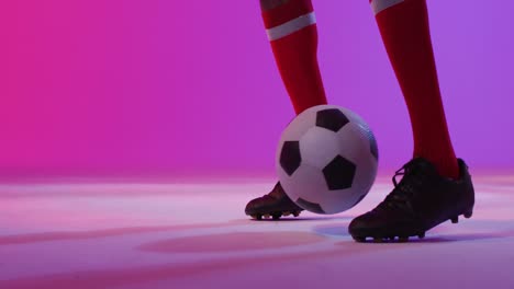 African-american-male-soccer-player-with-football-over-neon-pink-lighting