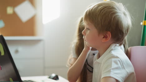 Das-Mädchen-Schaut-Auf-Den-Laptop-Und-Beugt-Sich-Zum-Jungen,-Der-Heimlich-Spricht