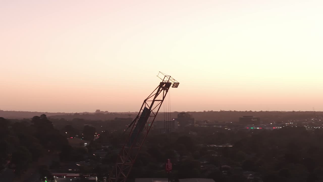 Betagende silhuet af en kran mod en strålende Melbourne solnedgang i Ringwood. Varme nuancer oplyser horisonten, hvilket skaber en dramatisk kontrast. Perfekt til bybilledtemaer.