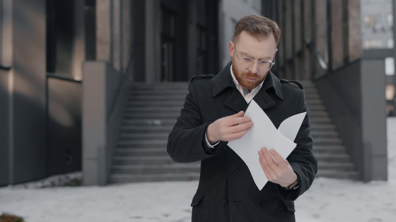 Мужчина в пальто читает документы на лестнице