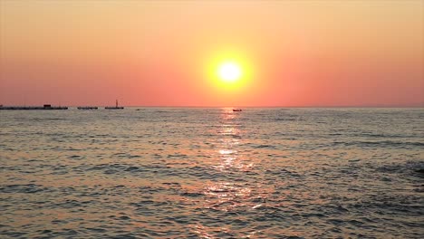 Beautiful-colorful-sunset-with-small-boats-swimming-on-the-horizon