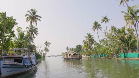 A-traditional-houseboat-approaches-along-a-canal-with-modern-boats-and-modern-coloured-walls-lining-the-banks-in-the-midday-sun