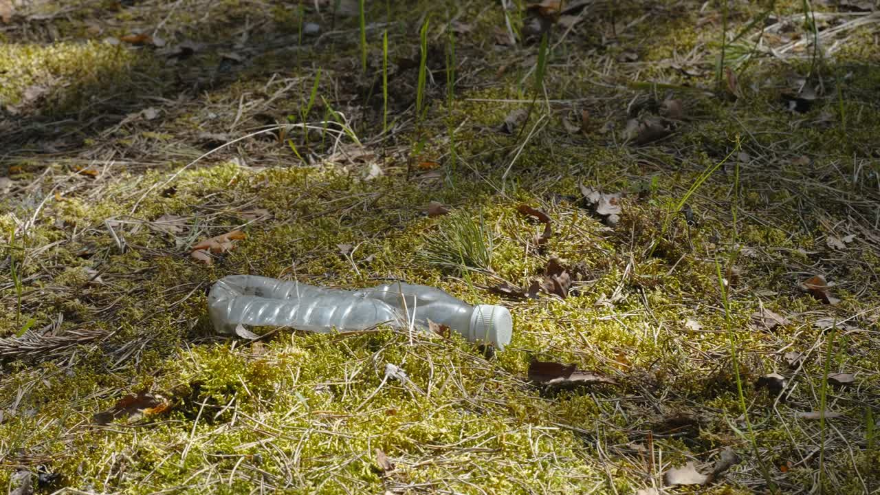 una botella de plástico arrugada en el suelo del bosque en estonia